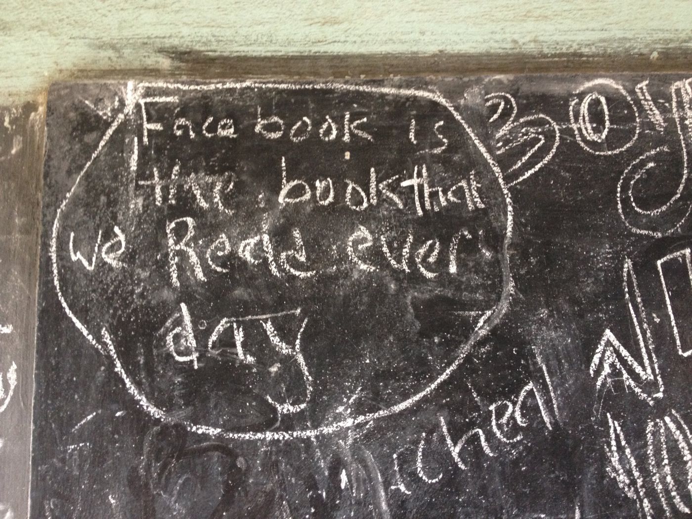 Chalk writing on a classroom blackboard: Facebook is the book that we read every day.