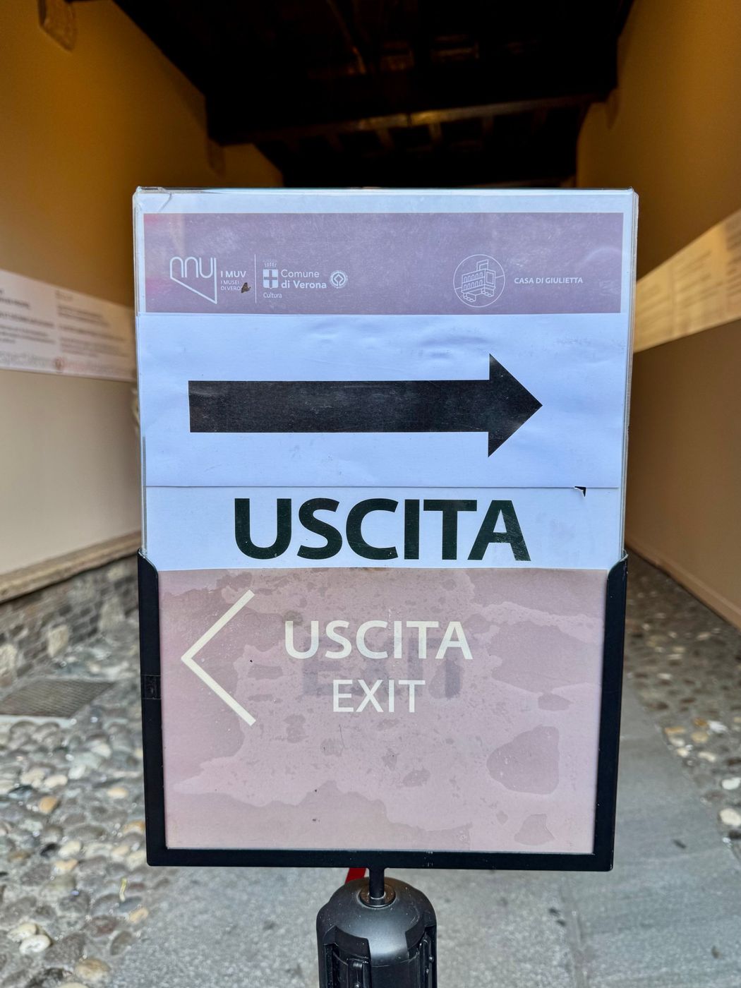 A sign reading Uscita with an arrow to the right, above a second Uscita sign pointing left.